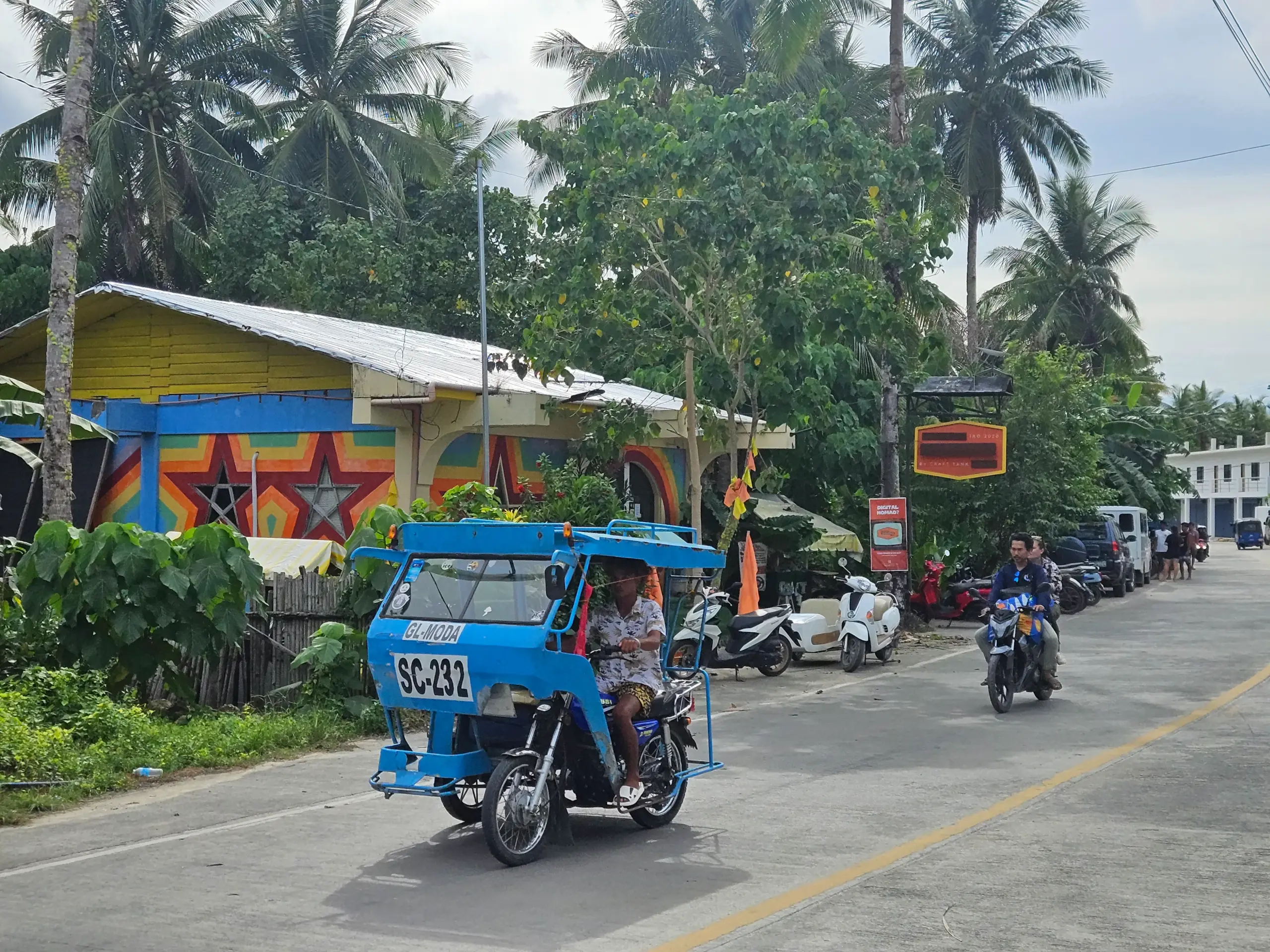 Blue motorized tricycle on palm-lined tropical street in Siargao
