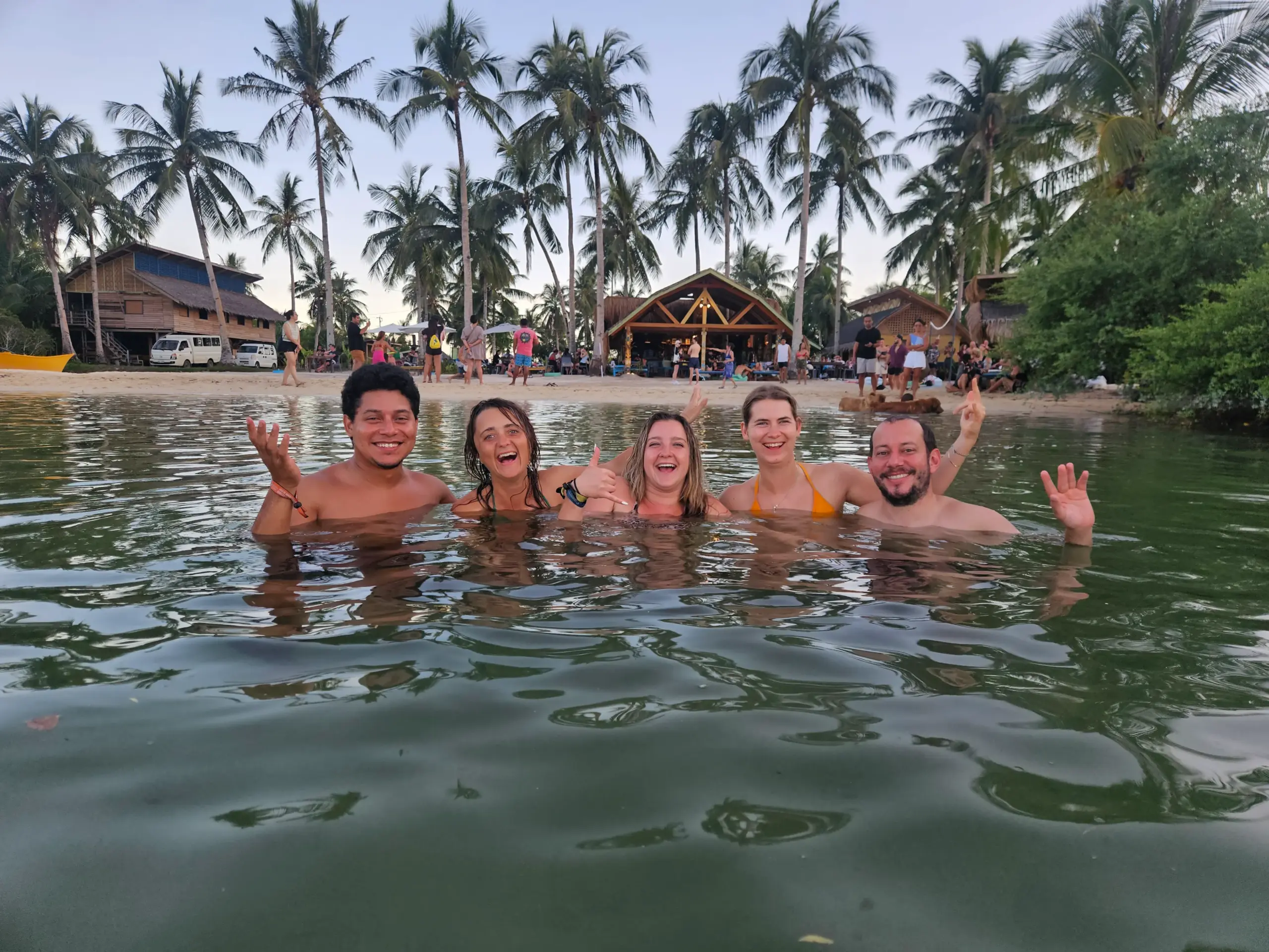 Friends laughing in sunset swim — group bonding excursion Nomads in Paradise Siargao