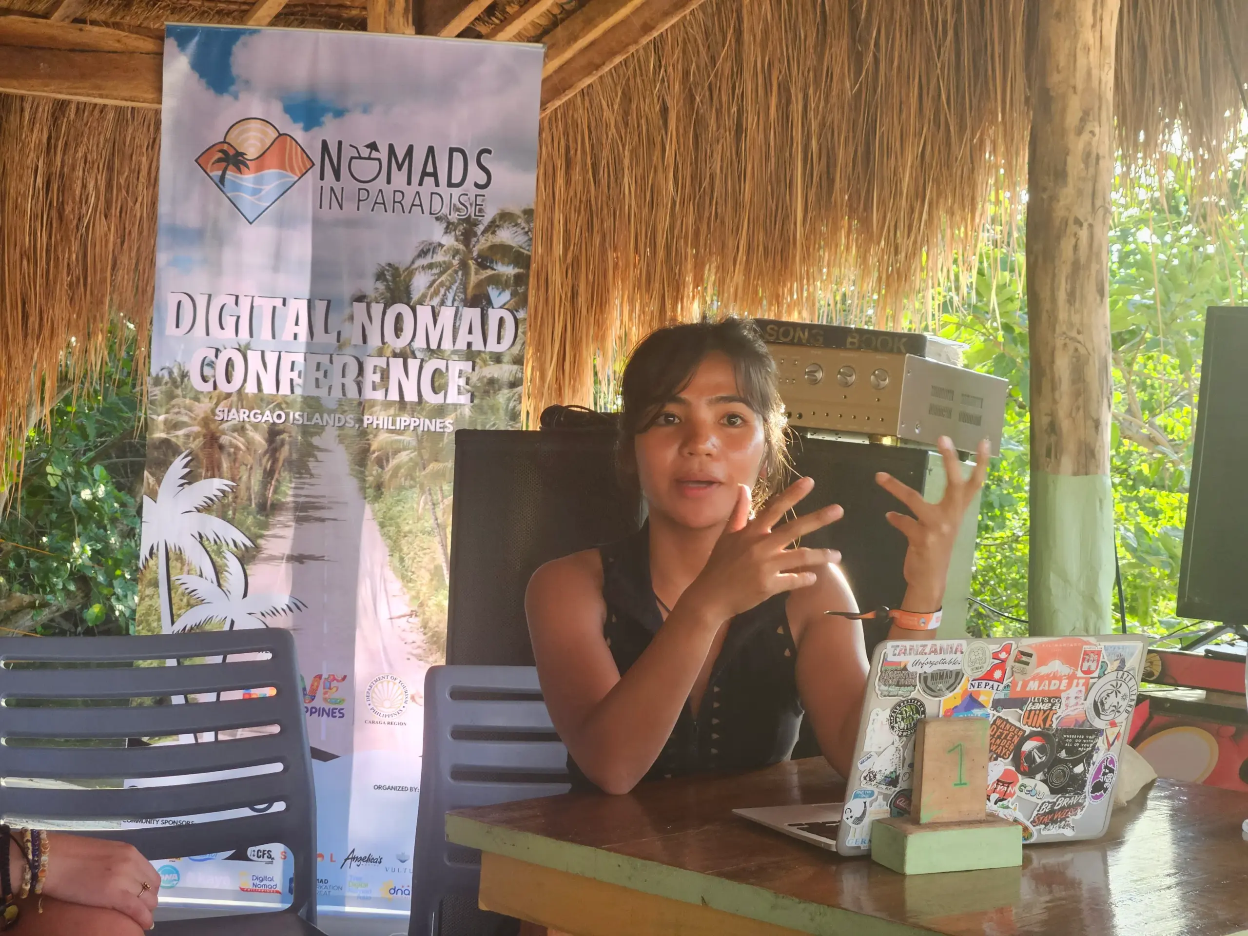 Workshop speaker with sticker-covered laptop at outdoor Nomads in Paradise venue