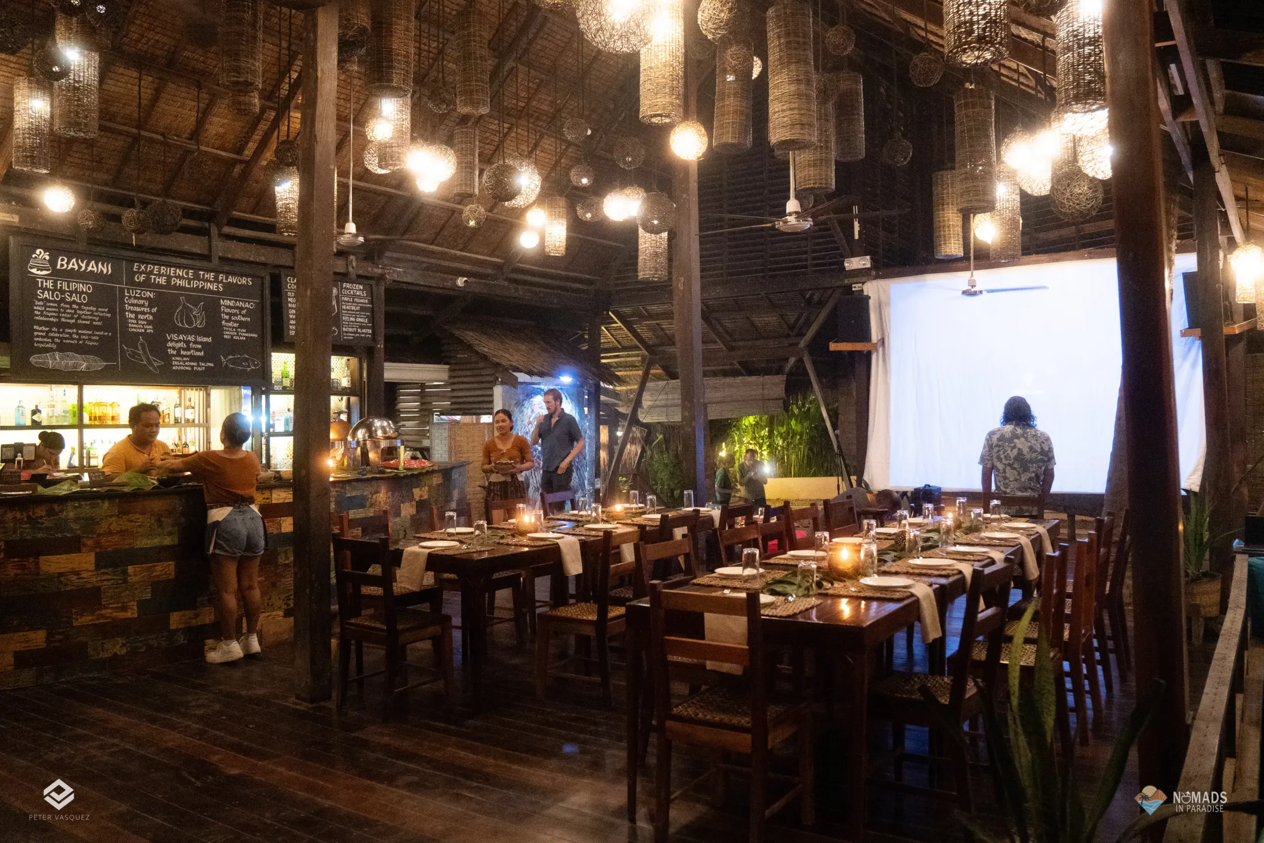 Lantern-lit open-air dining hall with set tables at tropical venue in Siargao