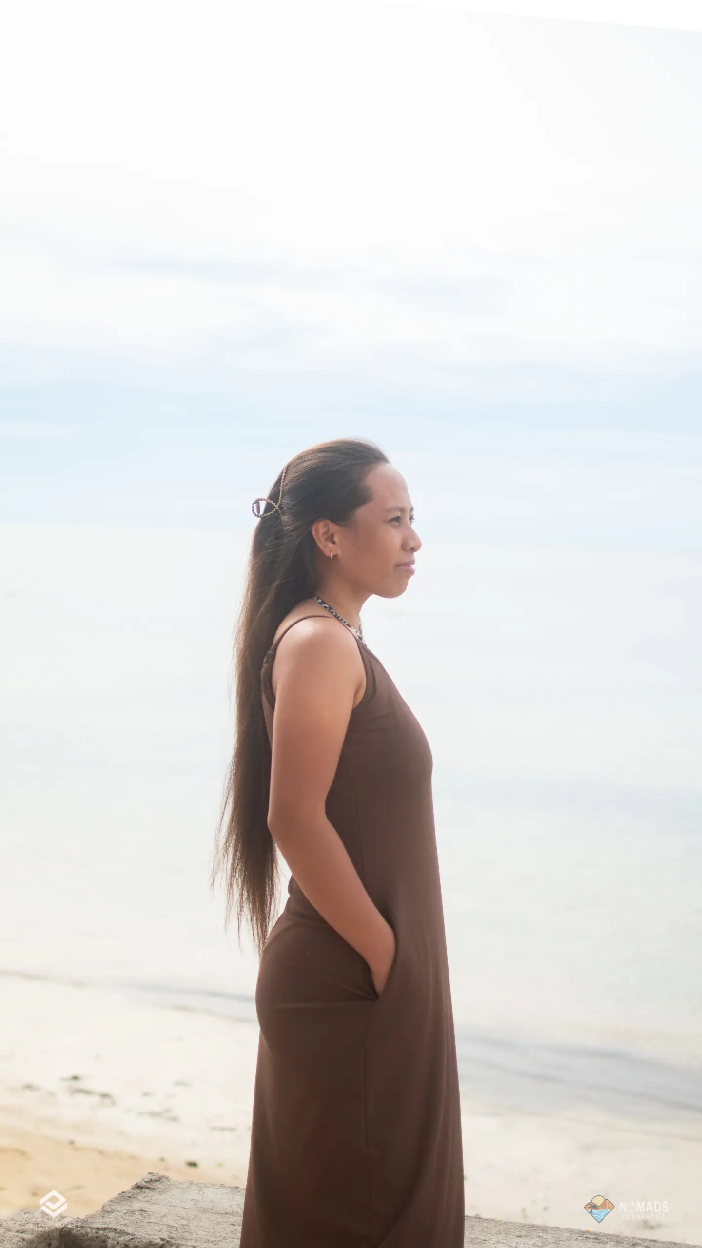 Woman in profile facing calm ocean on Siargao beach at Nomads in Paradise