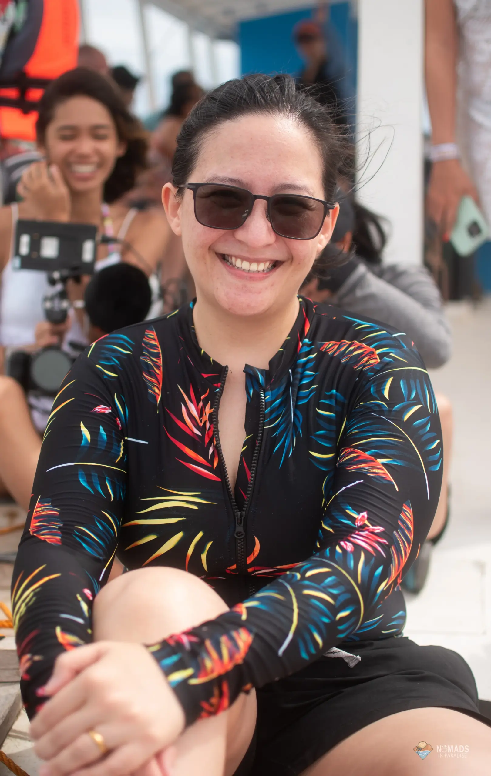 Smiling woman in colorful palm-leaf rash guard on Nomads in Paradise boat excursion