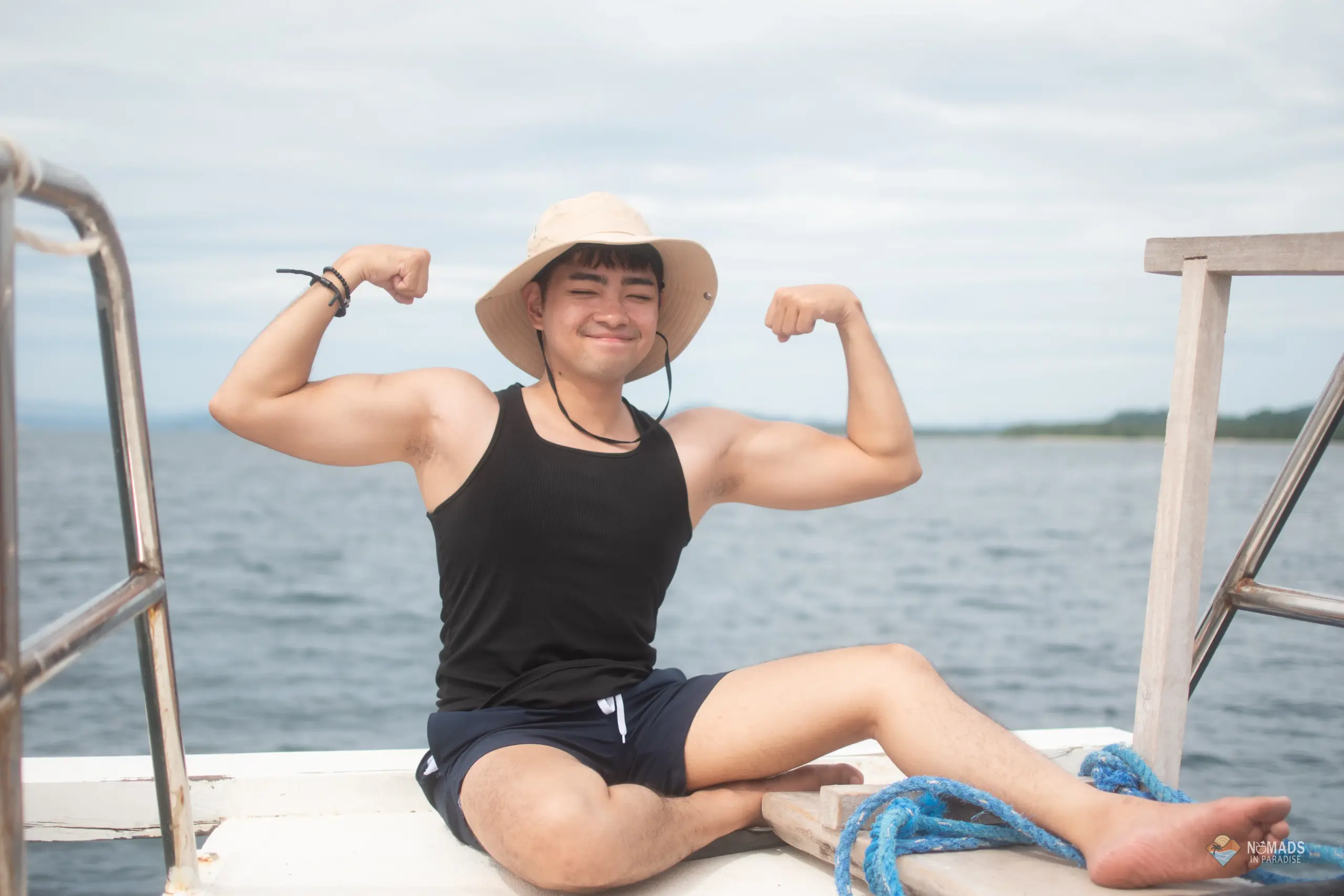 Young man flexing joyfully on boat deck during Nomads in Paradise island excursion