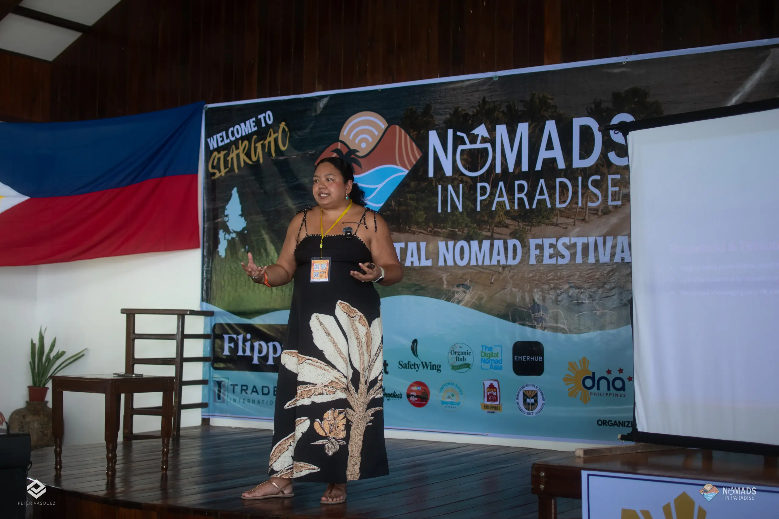 Speaker gesturing on Nomads in Paradise festival stage with Welcome to Siargao branding