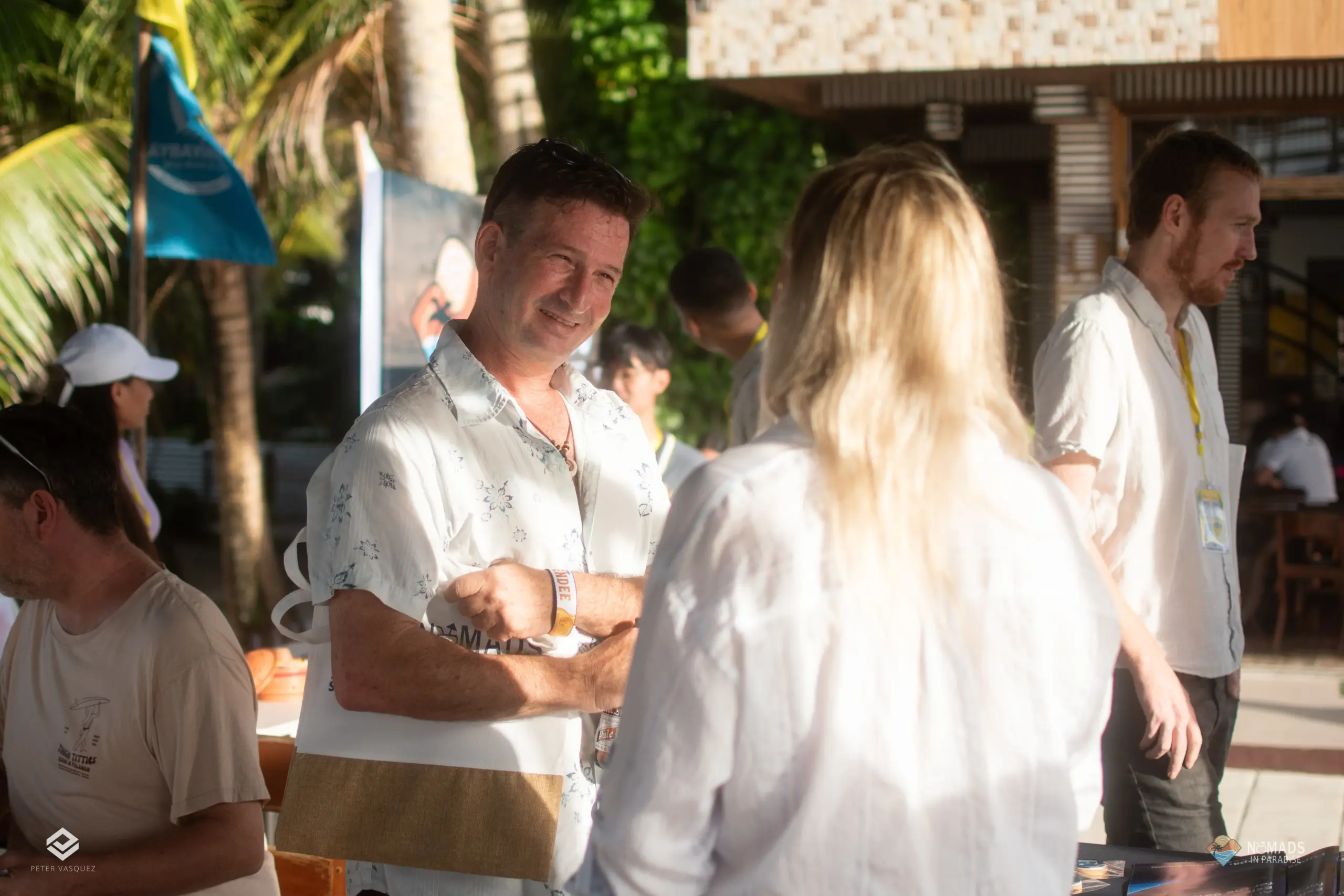 Smiling Nomads in Paradise attendee chatting outdoors with palm trees and bright sunlight