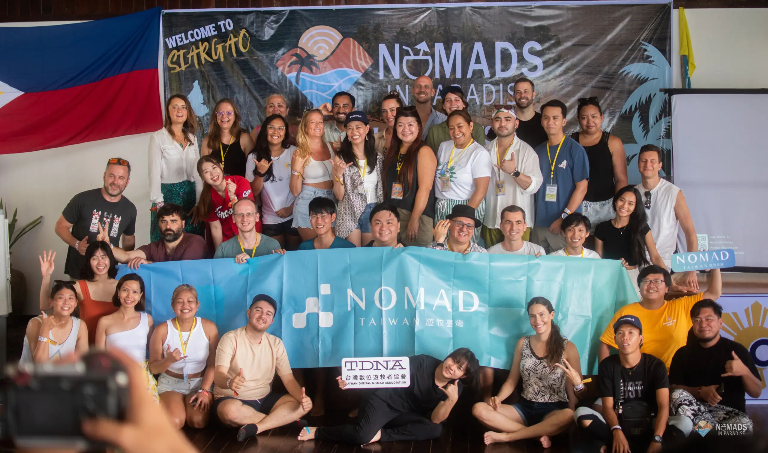 Large diverse group holding Nomad Taiwan banner at Nomads in Paradise festival