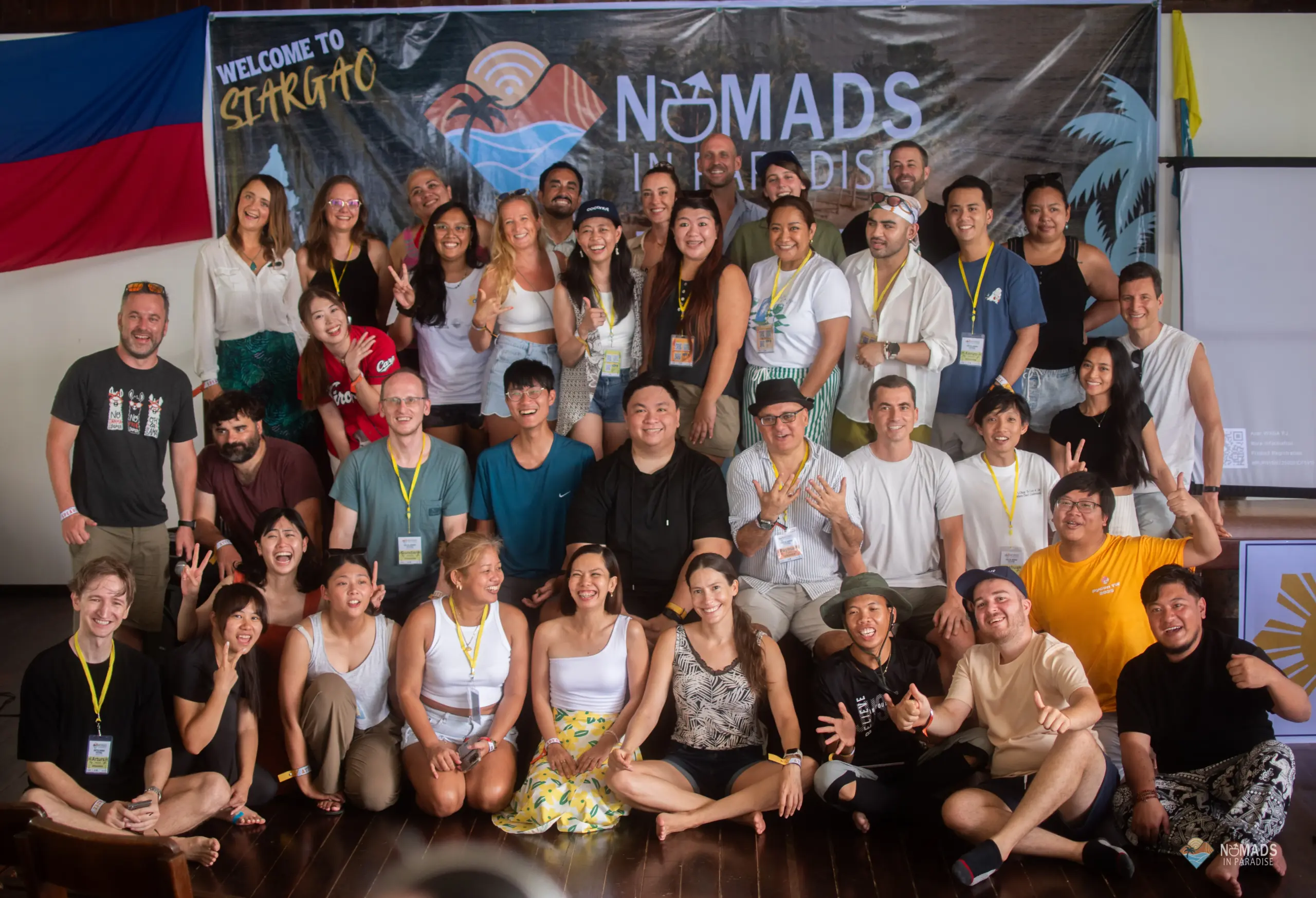 Large multi-row group of Nomads in Paradise attendees before festival banner — digital nomad event Philippines